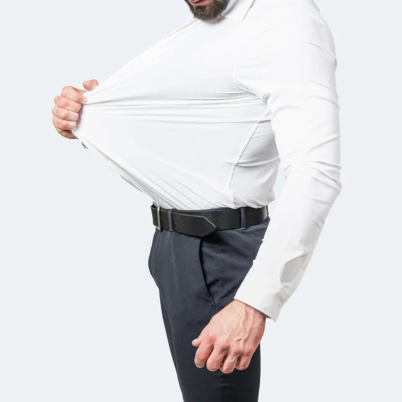 Man in white dress shirt stretching fabric to show elasticity, wearing black belt and dark pants
