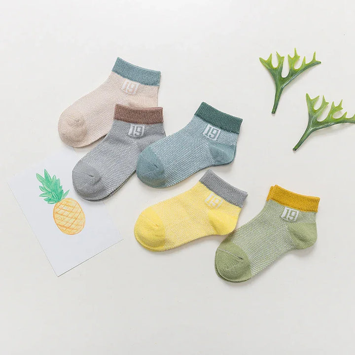 Set of five colorful ankle socks in pastel shades with '19' logo, displayed with pineapple drawing and green leaves