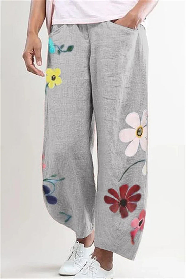 Gray wide-leg pants with colorful large floral prints worn with white sneakers