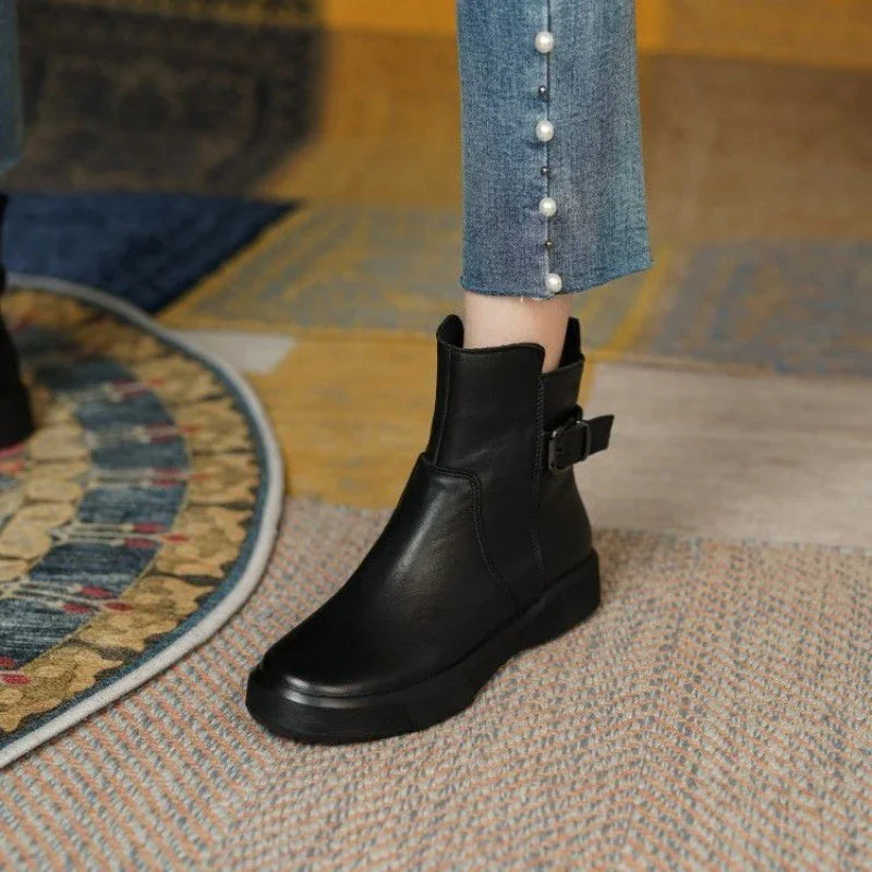 Black leather ankle boots with buckle detail worn with blue jeans featuring pearl buttons