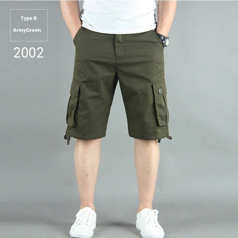Man wearing army green cargo shorts with pockets, white sneakers, and a white shirt on gray background