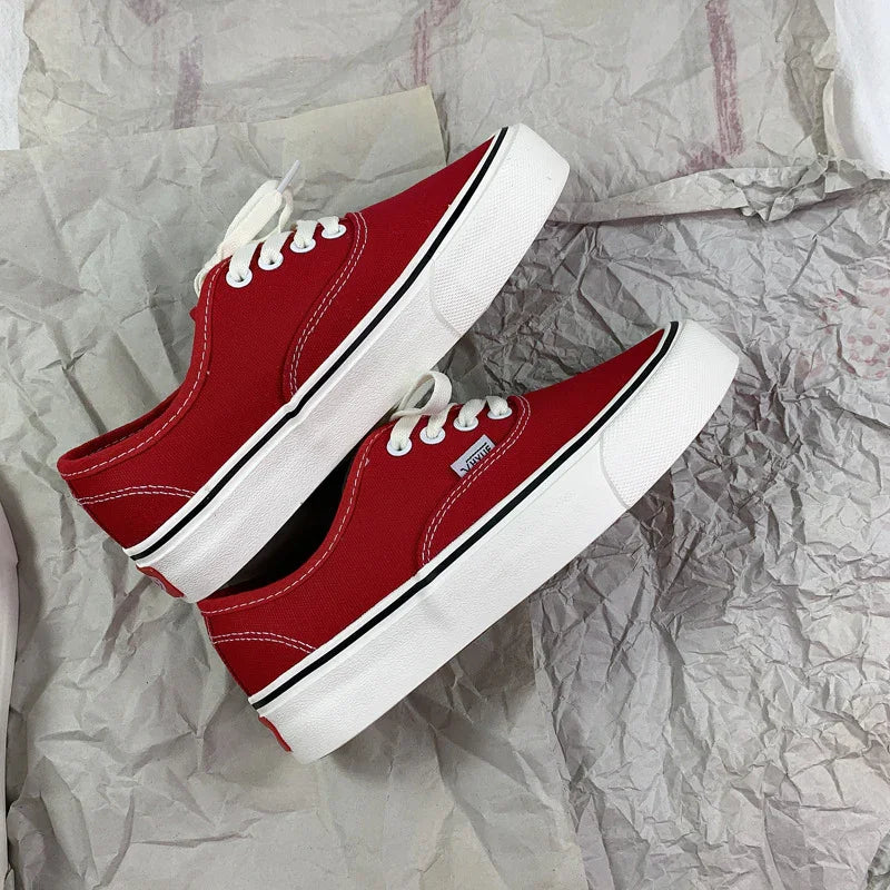 Pair of red Vans low-top canvas sneakers with white laces and thick white soles on crumpled paper
