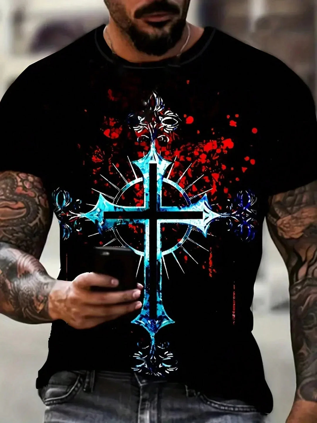 Man with tattoos wearing black t-shirt featuring blue decorative cross design and red splatter background