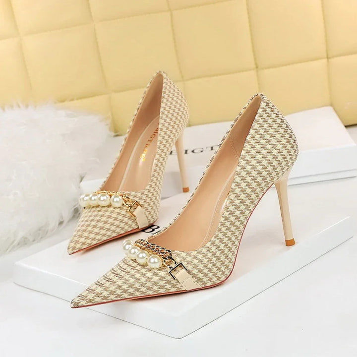 Beige houndstooth high heel pumps with pearl and chain embellishments on white box