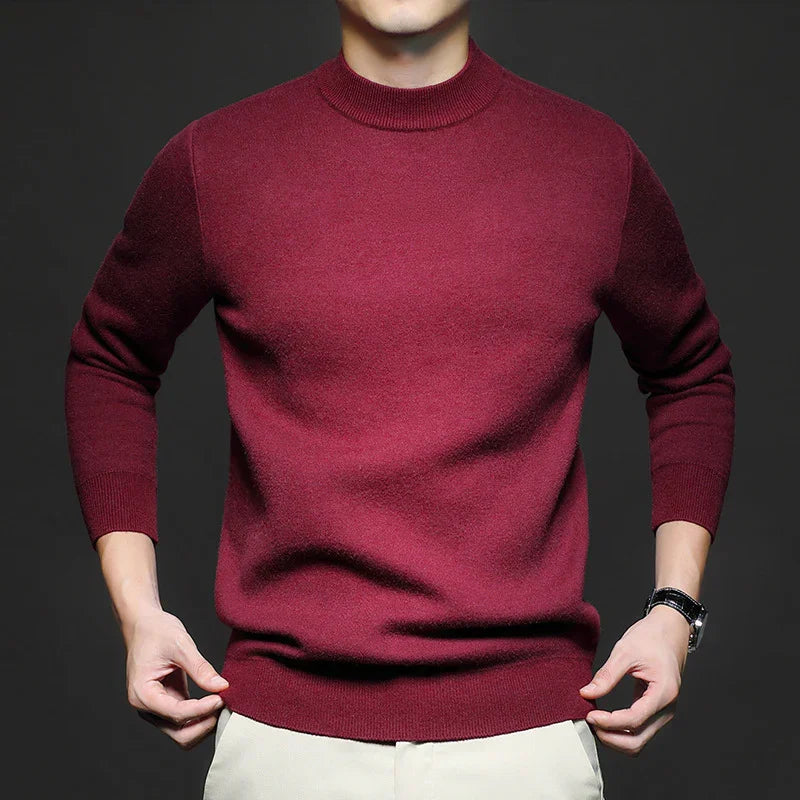 Man wearing a fitted maroon crewneck wool sweater with beige pants and black watch on dark background