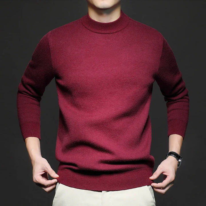 Man wearing a fitted maroon crewneck wool sweater with beige pants and black watch on dark background