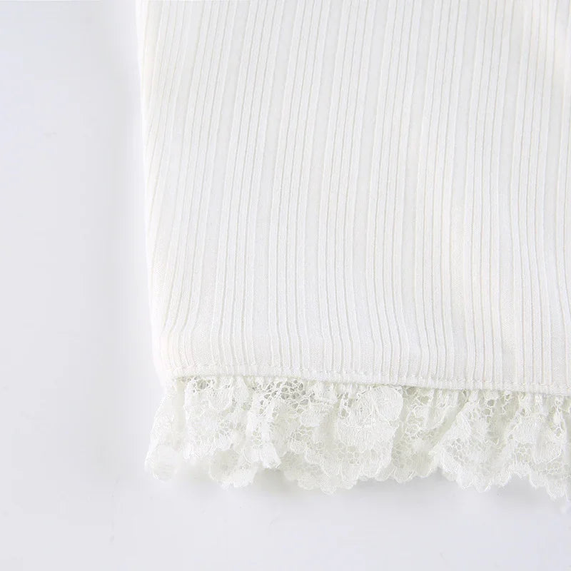 Close-up of white ribbed fabric with delicate lace trim detail at the edge