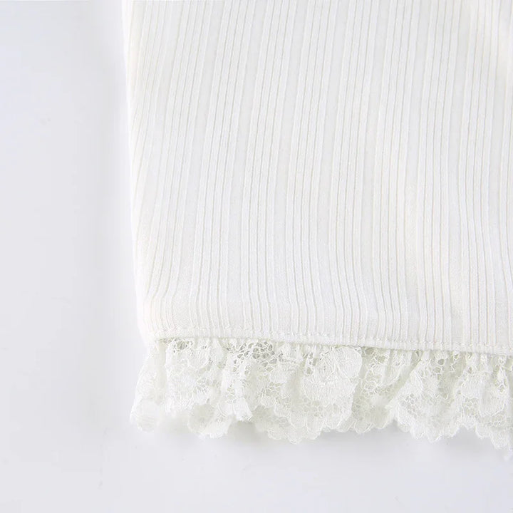 Close-up of white ribbed fabric with delicate lace trim detail at the edge