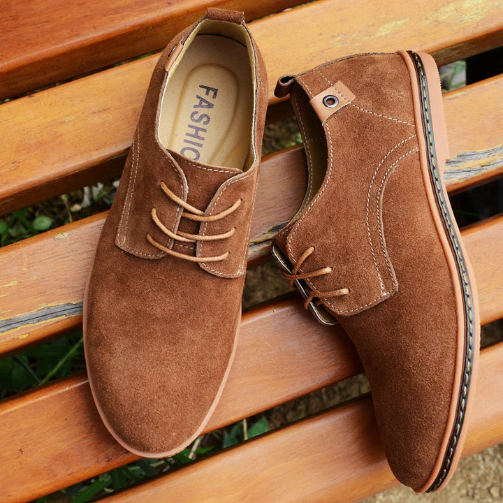 Brown suede casual men's shoes with laces on wooden bench outdoor