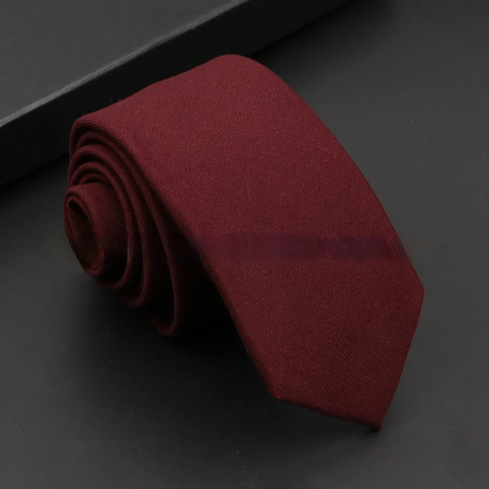 Rolled maroon necktie on black surface, classic solid color men's formal accessory