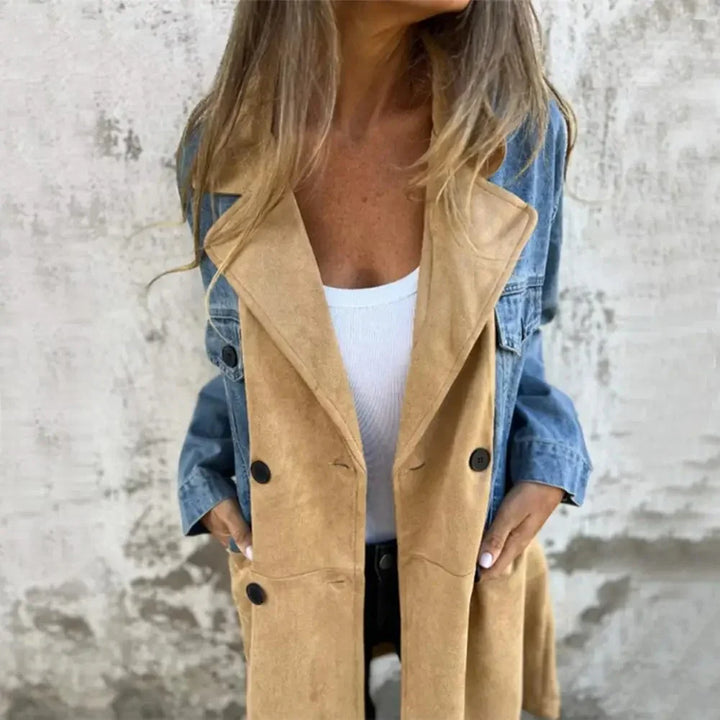 Woman wearing tan suede and blue denim jacket over white top against textured wall