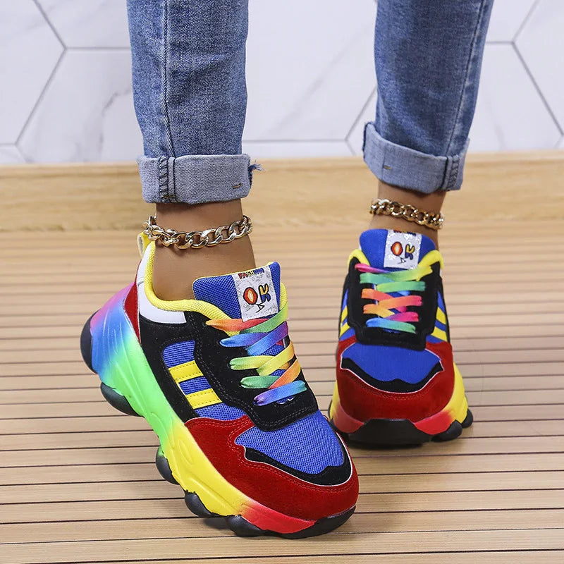 Colorful chunky sneakers with rainbow laces, blue mesh, red suede, and yellow accents worn with rolled jeans