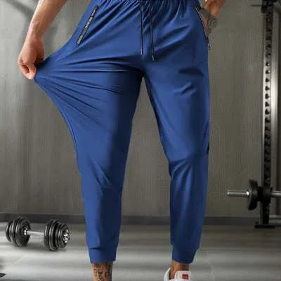 Man wearing stretchy blue jogger pants in gym with dumbbells and weight rack