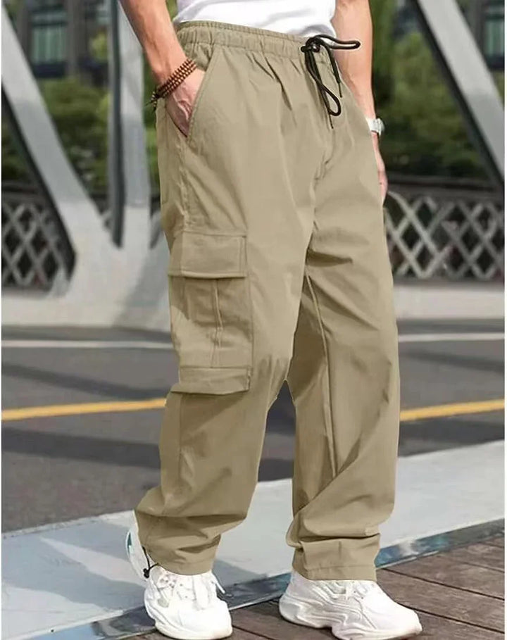 Man wearing beige cargo pants with elastic waistband and white sneakers on city street