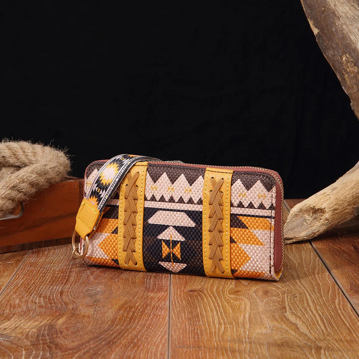 Aztec pattern wristlet wallet with brown, yellow, and orange woven fabric on wooden surface