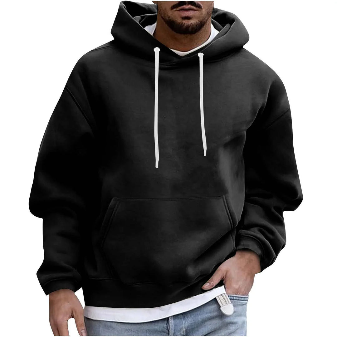 Man wearing black hoodie with white drawstrings and kangaroo pocket over white shirt and jeans