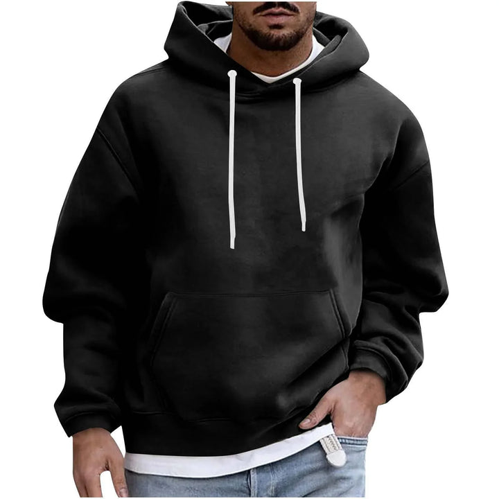Man wearing black hoodie with white drawstrings and kangaroo pocket over white shirt and jeans