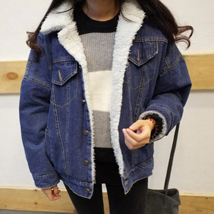 woman wearing blue denim jacket with white sherpa lining over striped sweater indoors