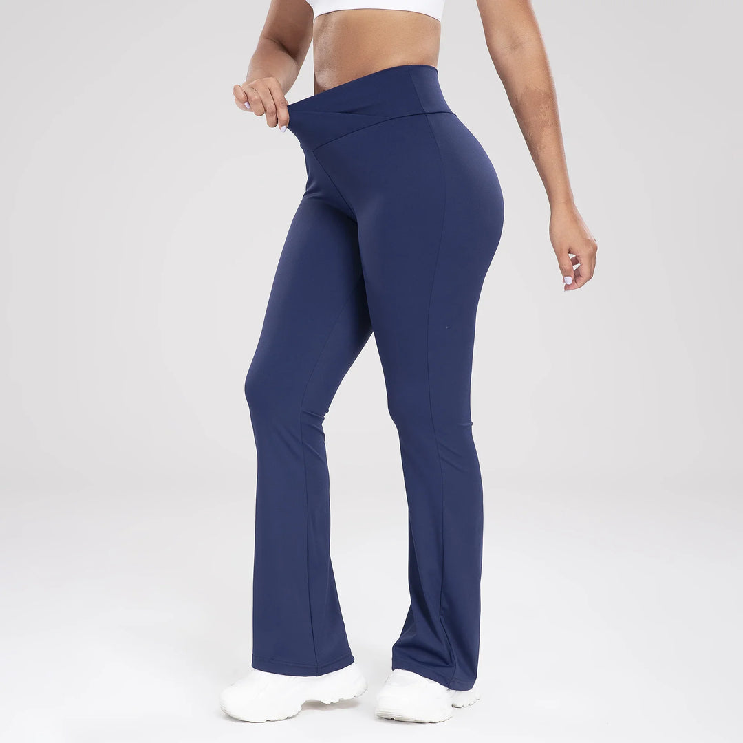 Woman wearing navy blue high-waisted flared leggings stretching waistband, white sneakers