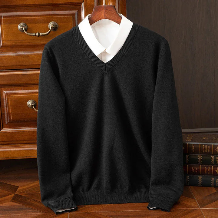 Black V-neck wool sweater layered over white collared shirt on wooden hanger with vintage books and drawers