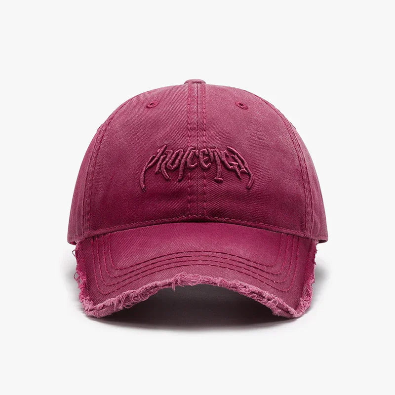 Front view of a vintage washed pink baseball cap with distressed edges and embroidered logo