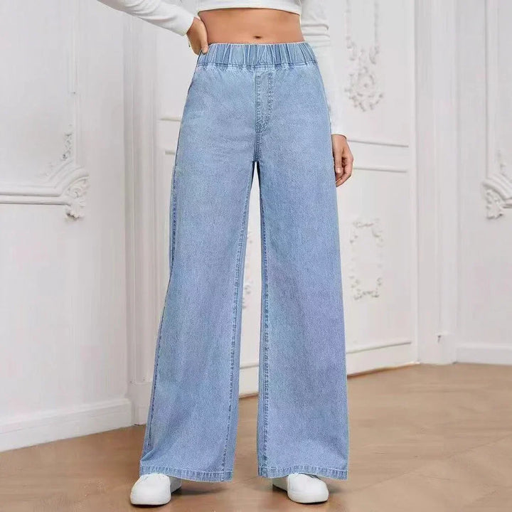Woman wearing light blue wide-leg high-waisted jeans with elastic waistband and white sneakers