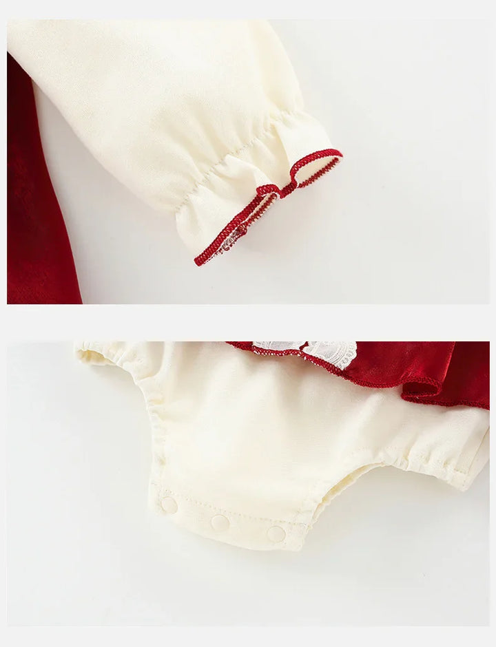 Cream-colored baby romper with red trim and snap closures on white background