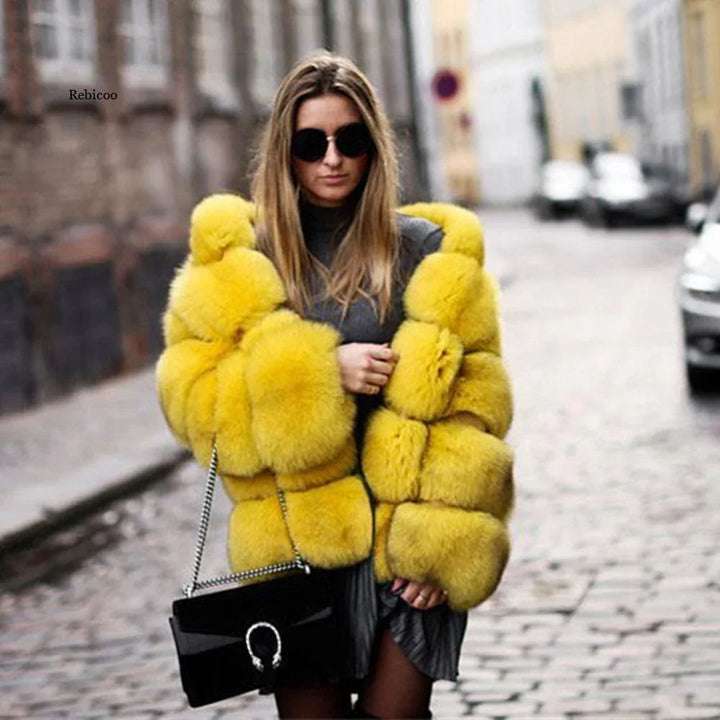 Woman wearing a bright yellow fur coat, black sunglasses, and holding a black handbag on a cobblestone street