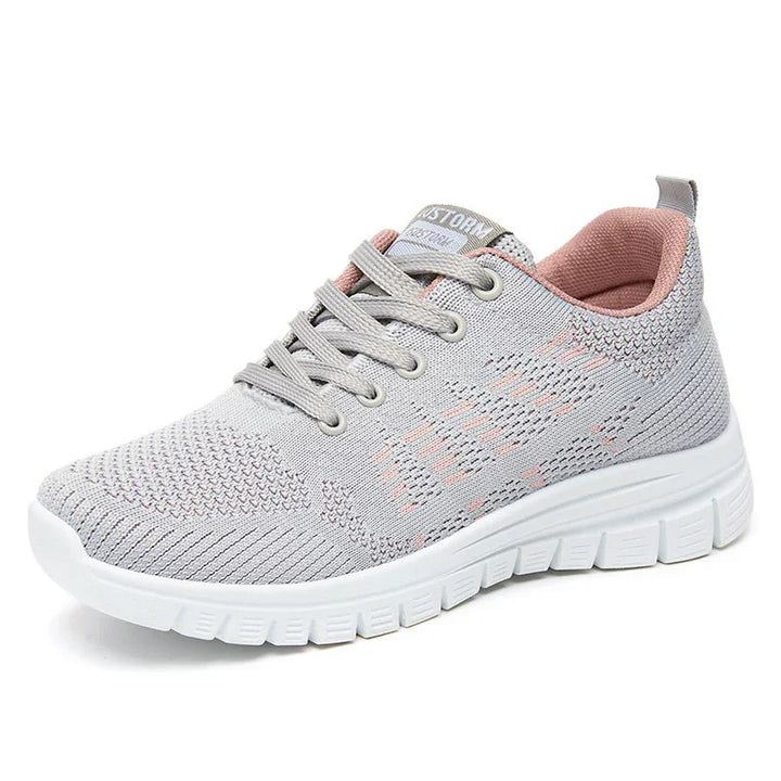 Light gray knitted athletic sneaker with white sole and pink inner lining, lace-up design