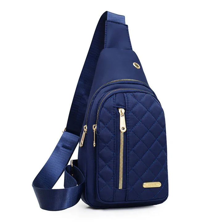 Navy blue quilted sling bag with gold zippers and adjustable shoulder strap