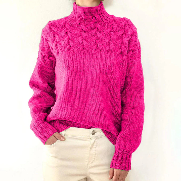 Woman wearing a vibrant pink cable knit turtleneck sweater with cream pants
