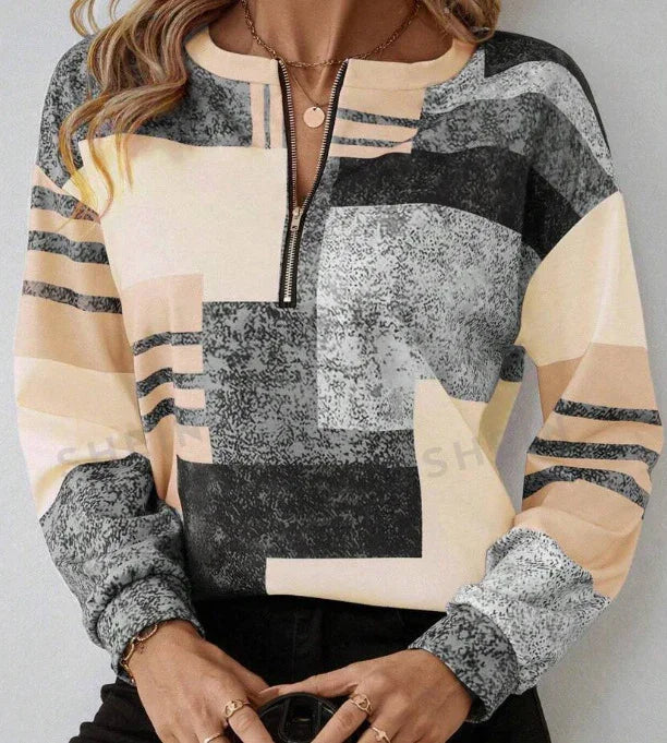 Woman wearing a long-sleeve geometric print pullover with front zipper neckline in beige, black, and gray