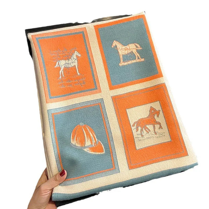Hand holding a folded fabric with horse and equestrian helmet prints in orange and teal squares