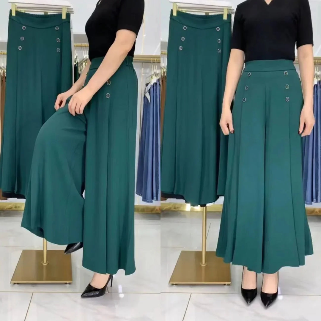 Woman modeling teal wide-leg pants with decorative buttons, paired with black top and heels in a boutique