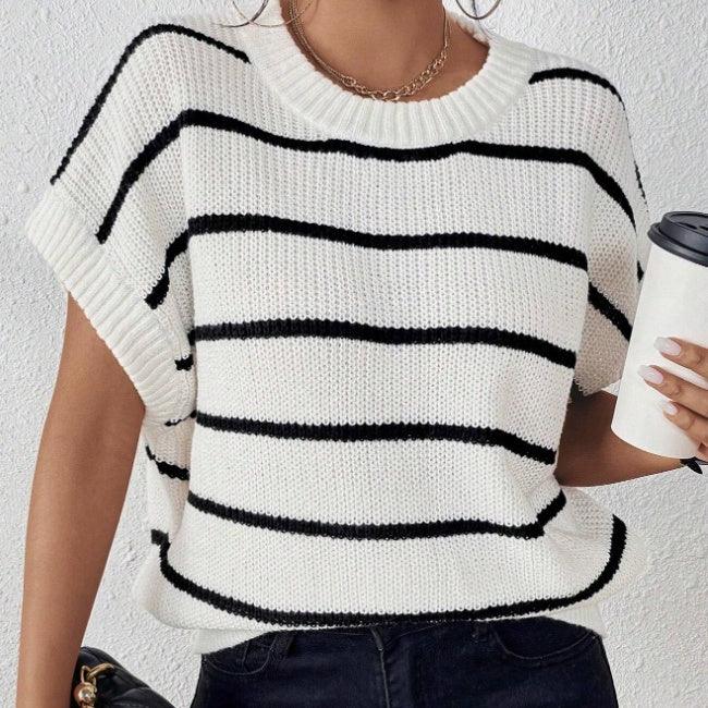 Woman wearing white knit sweater with black horizontal stripes holding coffee cup