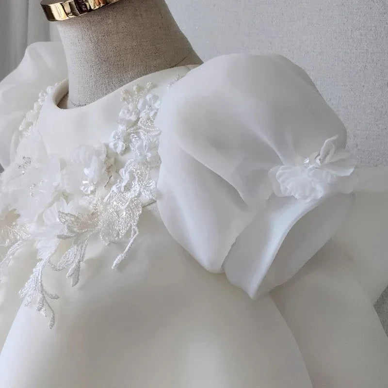 White dress with puff sleeves and floral lace applique on mannequin against gray background