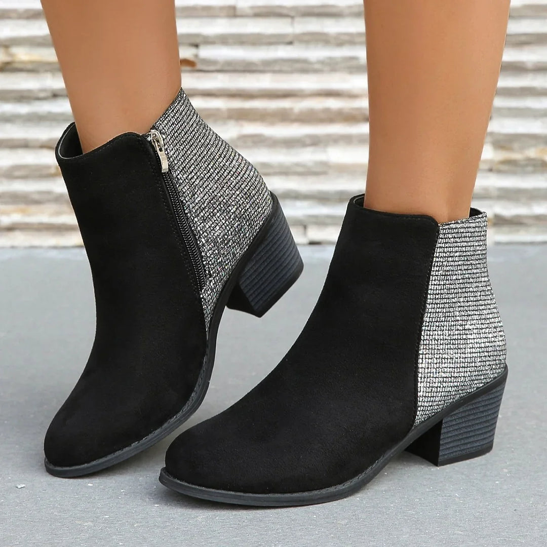 Black suede ankle boots with silver glitter back panels and block heels on concrete floor