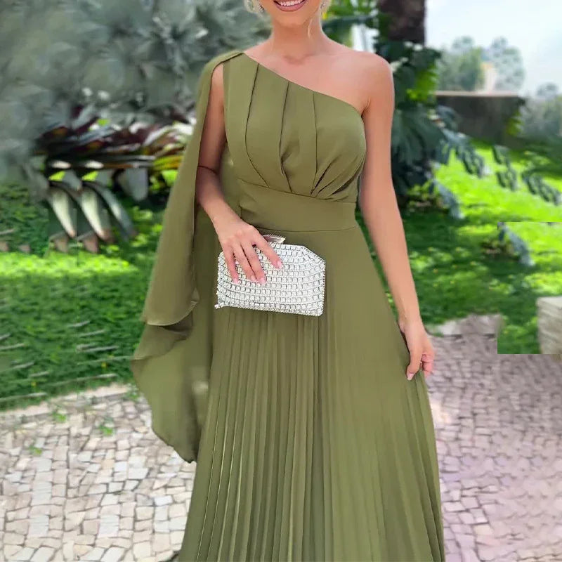 Woman wearing olive green one-shoulder pleated evening gown holding silver clutch in garden