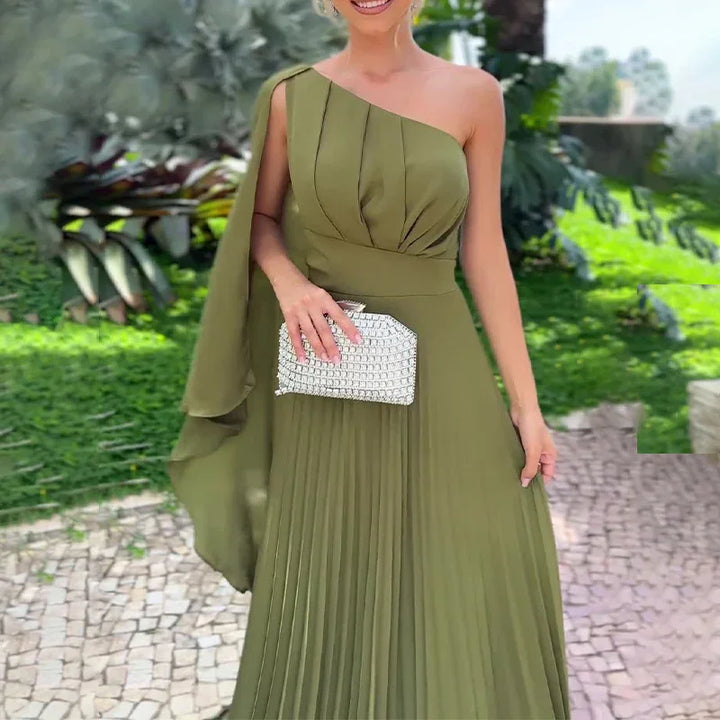 Woman wearing olive green one-shoulder pleated evening gown holding silver clutch in garden