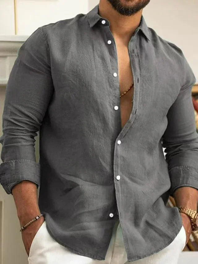 Man wearing casual grey linen shirt with rolled sleeves and white pants, accessorized with bracelet and watch