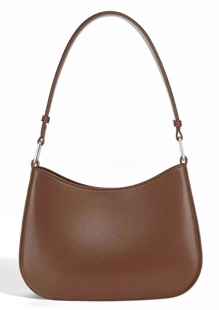 Brown leather shoulder bag with curved top and adjustable strap against white background