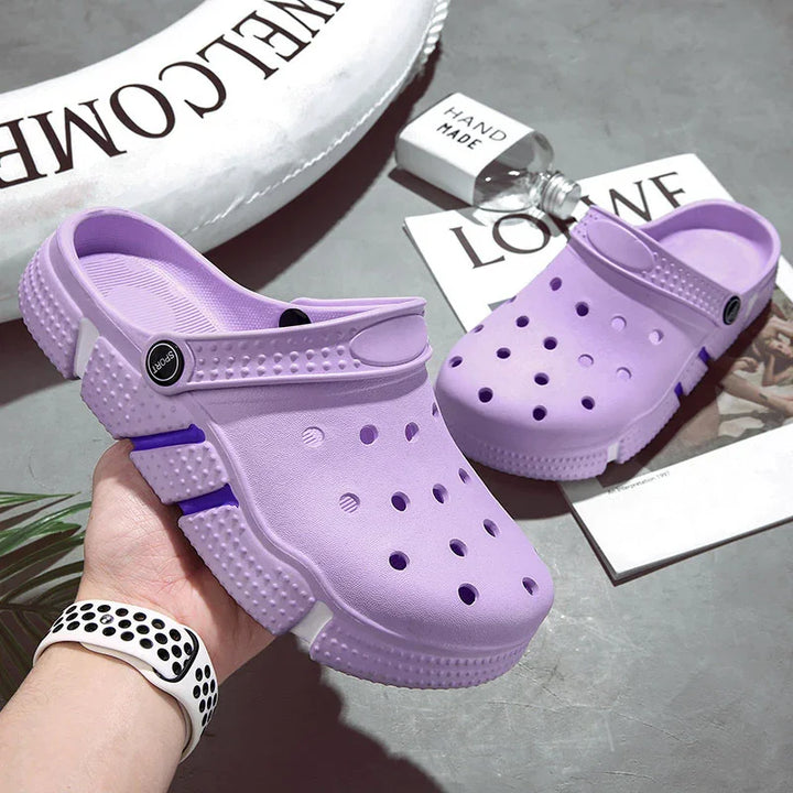 Pair of handmade purple slip-on clogs with ventilation holes and sporty design on gray surface