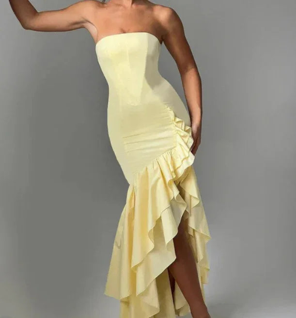 woman wearing strapless yellow ruffled mermaid evening gown on gray background