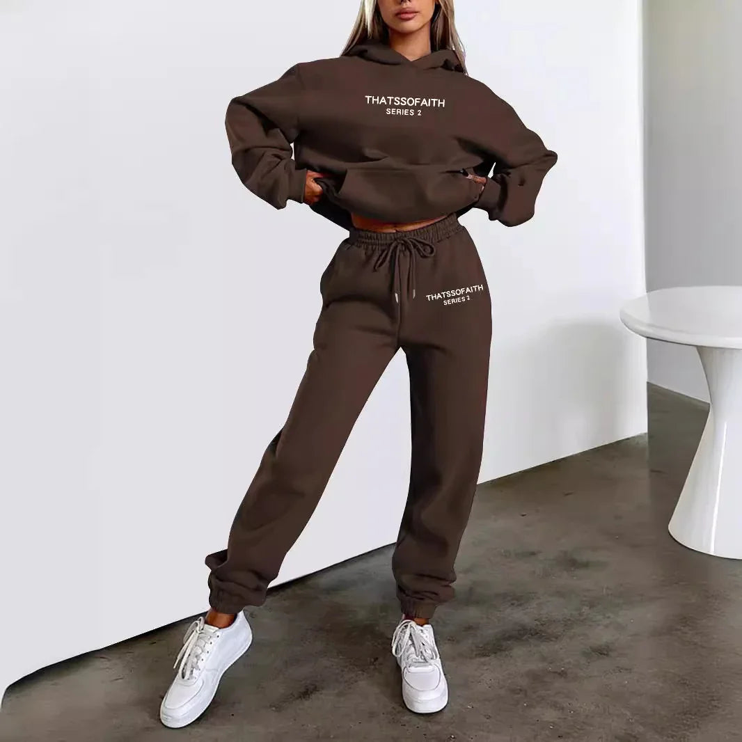 Woman wearing brown THATSSOFAITH Series 2 hoodie and joggers with white sneakers on concrete floor