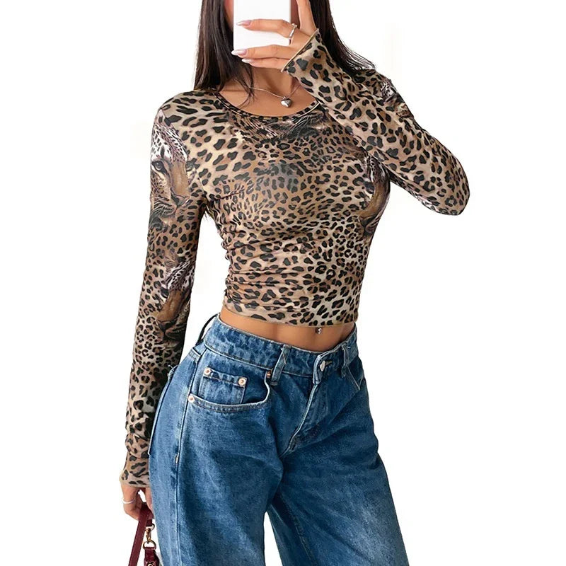 Woman wearing leopard print long sleeve crop top paired with high-waisted blue jeans against white background