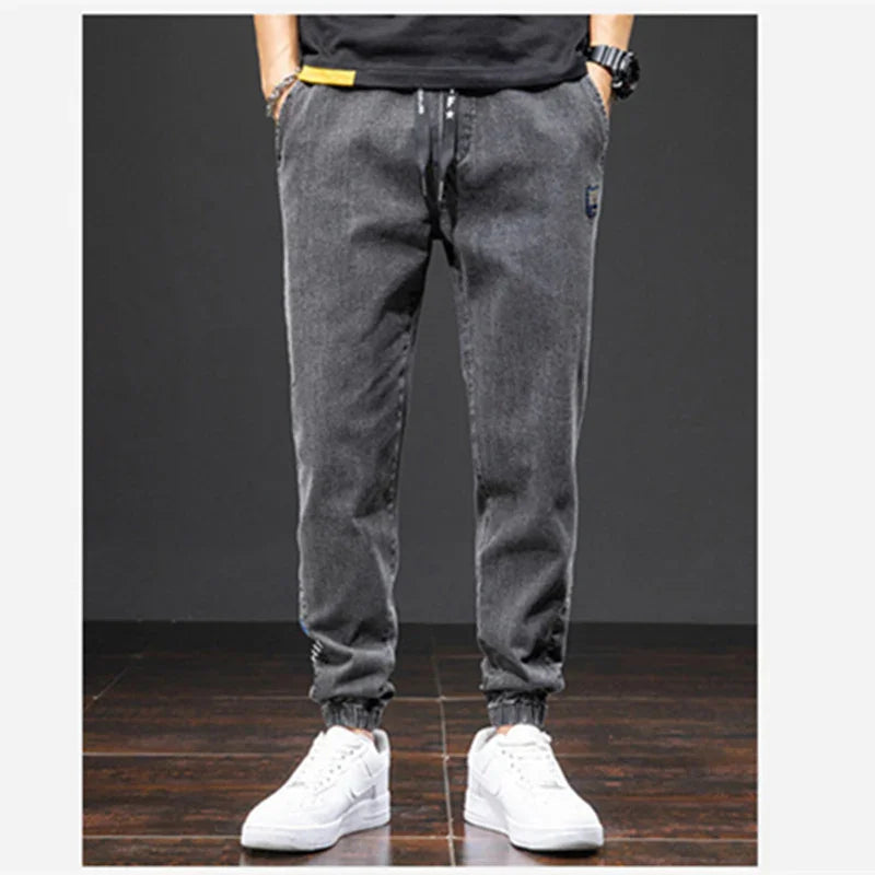 Men's gray casual jogger pants with elastic cuffs and white sneakers on wooden floor