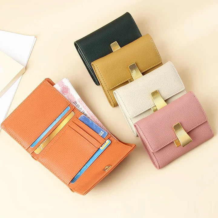 Five textured leather wallets in orange, pink, beige, mustard, and black with gold clasps on beige background