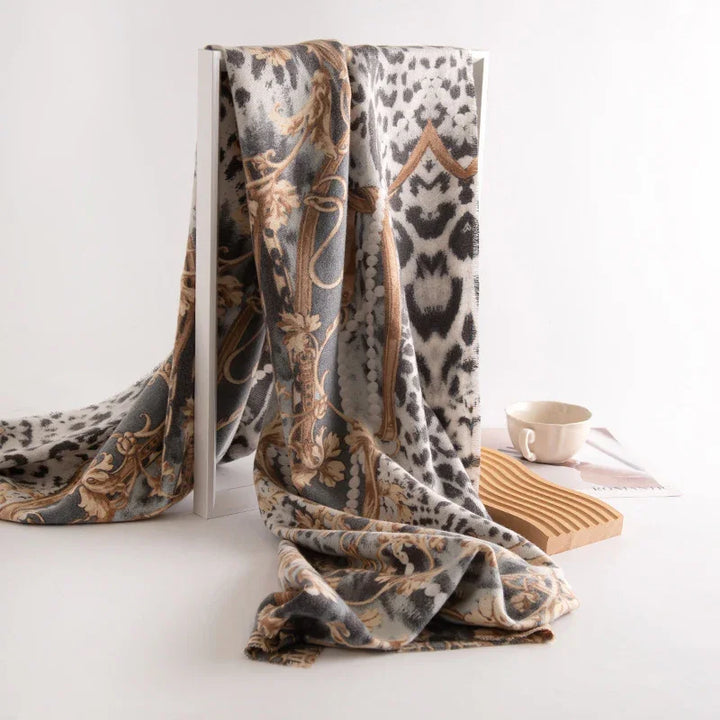 Soft patterned scarf with leopard print and beige floral design draped over white frame, cup and wooden coaster nearby