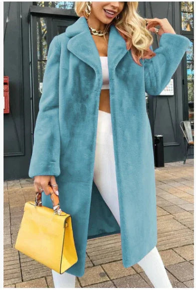 Woman wearing a long blue faux fur coat over white outfit, holding a yellow handbag outdoors