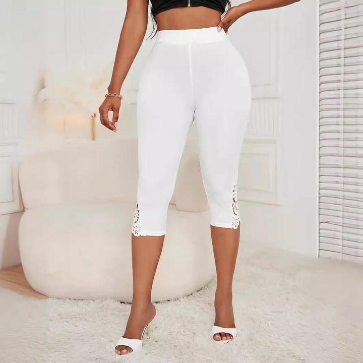 Woman wearing white cropped leggings with lace detail at hem and white heeled sandals in stylish room